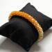 Orange Creamsicle Kumihimo bracelet with orange and ivory glass seed beads on black display pillow